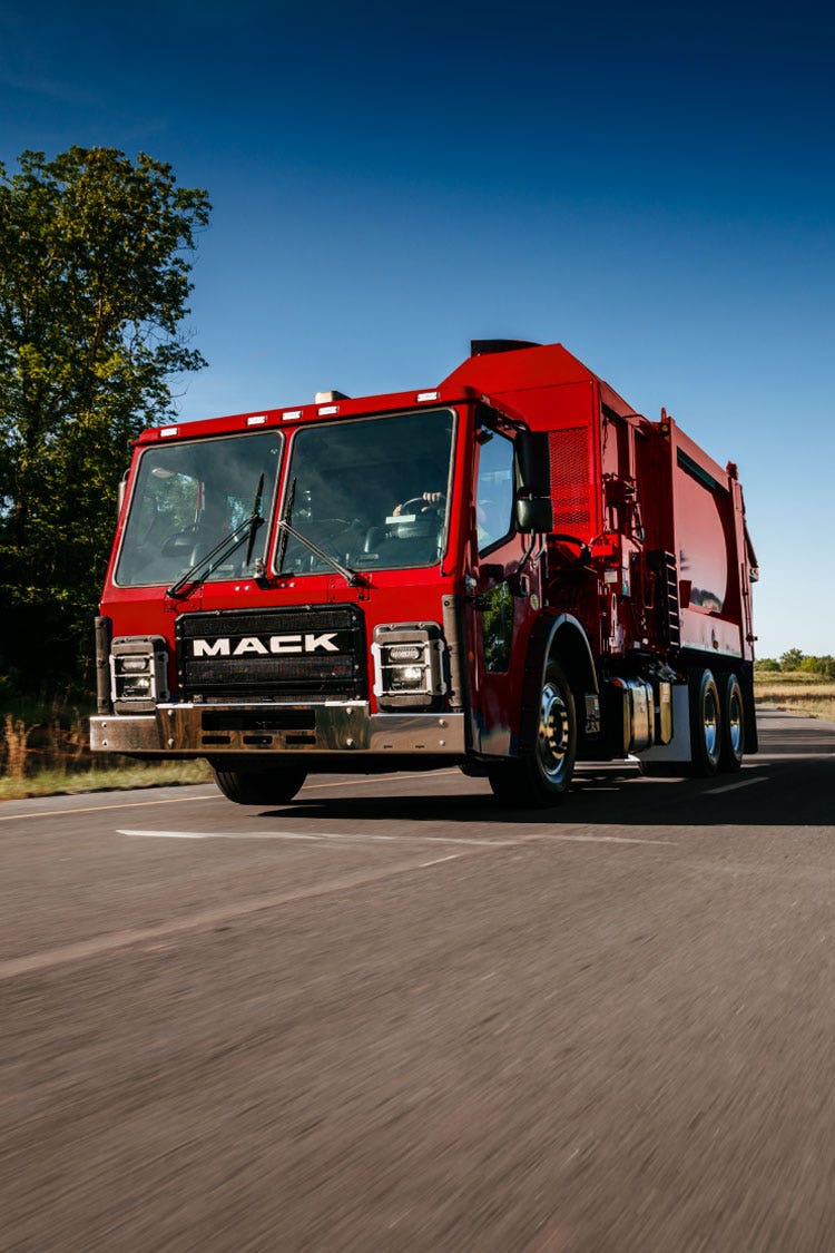 A red Mack LR Series truck, designed for refuse collection with a durable cab and bold Mack branding