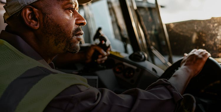 Close-up of a driver in a Mack LR Series truck cab, focused on operating the vehicle.