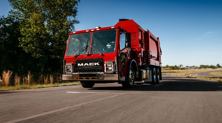 A red Mack LR Series truck, designed for refuse collection with a durable cab and bold Mack branding
