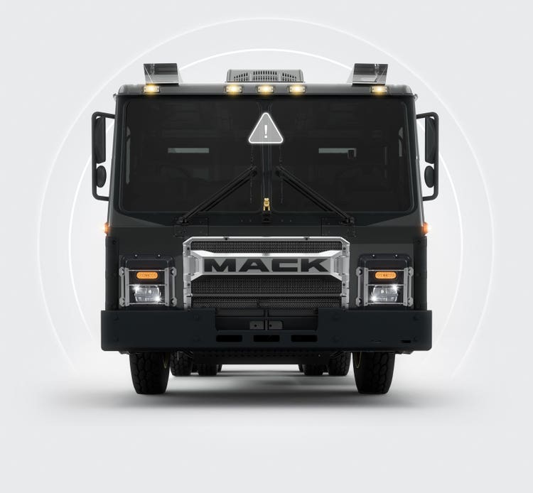 Front view of a Mack LR Series truck showcasing its blind spot detection system, indicated by an alert icon and circular detection signals around the vehicle