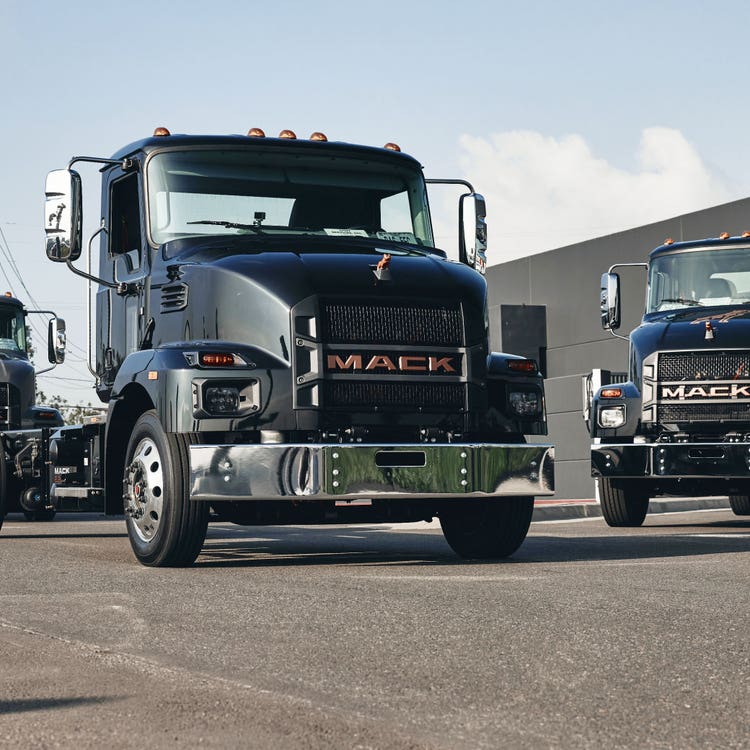 A group of Mack MD trucks parked on a concrete surface.
