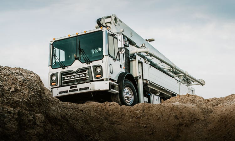 Mack TerraPro concrete pump truck delivering concrete to a construction site.