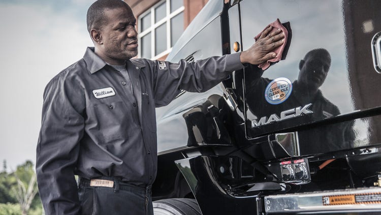 A person cleaning the hood of a Mack Truck.
